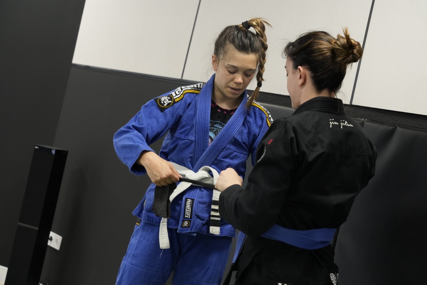 Dos alumnas se ayudan a ajustarse el cinturón en NEKO Jiu-Jitsu